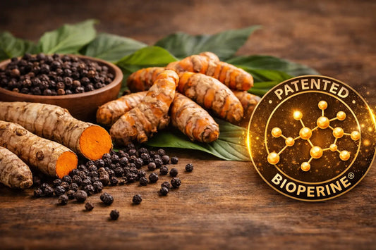 fresh turmeric roots and black peppercorns on green leaves on a wooden surface, representing natural ingredients used to support curcumin absorption