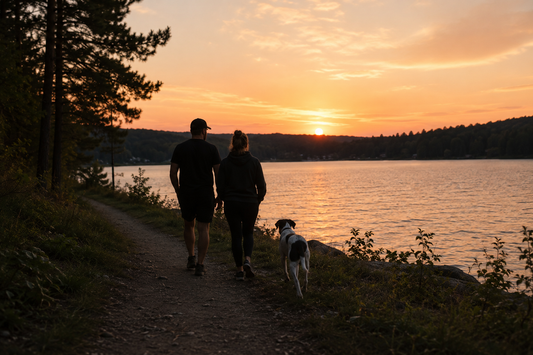 Couple walking with their German shorthaired pointer along a lakeside trail at sunset in Minnesota surrounded by pine trees and calm water