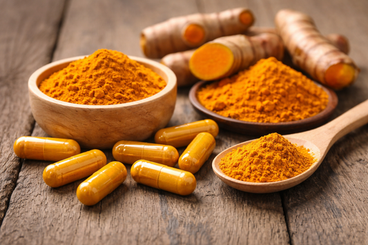 turmeric capsules, turmeric root, and turmeric powder on wooden surface illustrating turmeric dosage for joint support