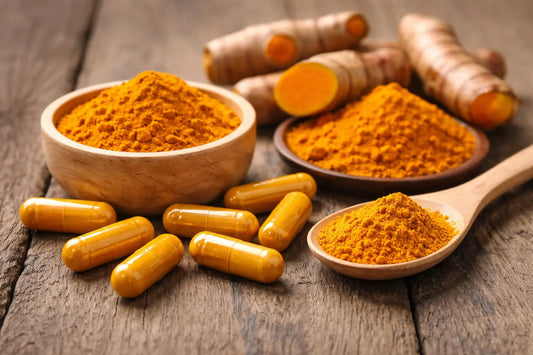 turmeric capsules, turmeric root, and turmeric powder on wooden surface illustrating turmeric dosage for joint support