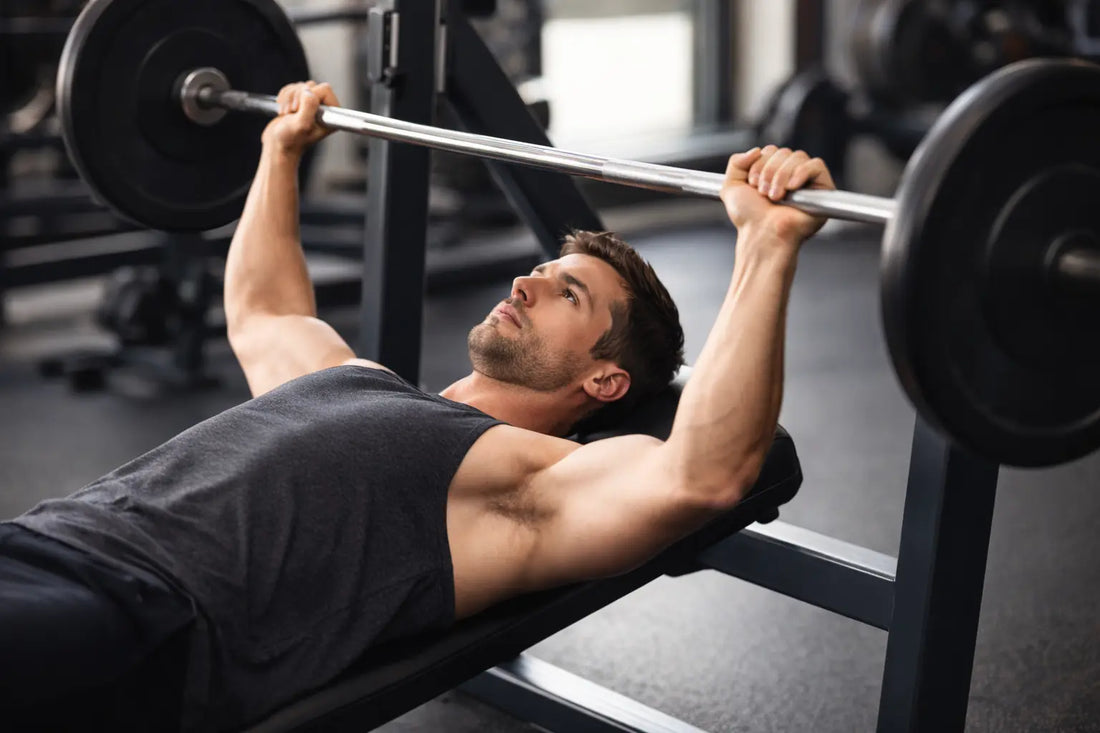 man performing a bench press with the barbell lifted slightly above his chest, demonstrating proper lifting form in a gym setting