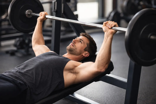 man performing a bench press with the barbell lifted slightly above his chest, demonstrating proper lifting form in a gym setting