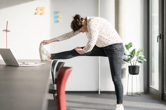 woman stretching leg on office desk after sitting long time to relieve joint stiffness