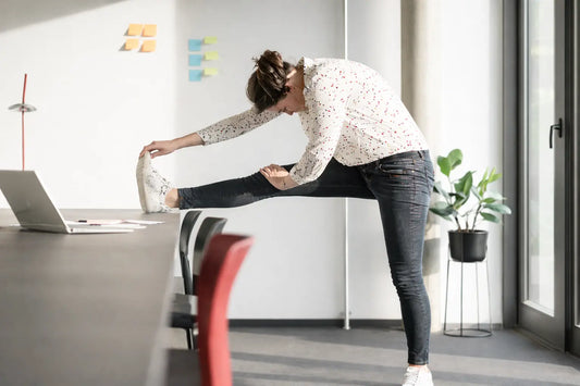 woman stretching leg on office desk after sitting long time to relieve joint stiffness